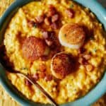 Pumpkin risotto with scallops and pancetta in a bowl.