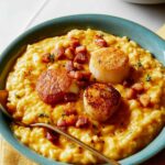 Two bowls of pumpkin risotto topped with scallops.