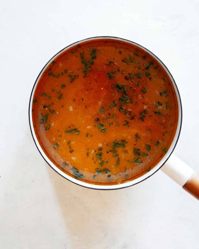 Combining the pumpkin purée with the stock in a pot for Pumpkin Soup.