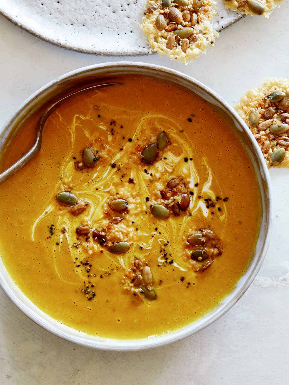 A close up on Creamy Pumpkin Soup with crème fraîche drizzled on the top. 