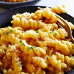 A bowl of Pumpkin Mac and Cheese with a fork spearing some pasta.