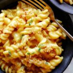 A bowl of pumpkin mac and cheese for a fork in the pasta.