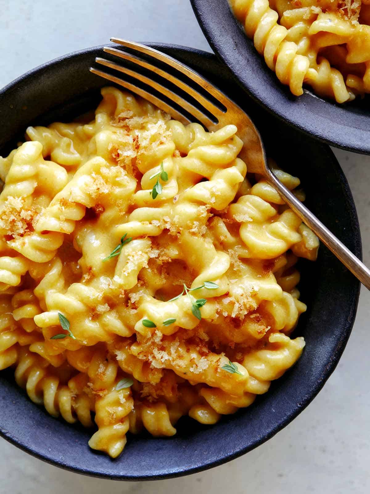 Pumpkin Mac and Cheese served into two bowls with a fork in one. 