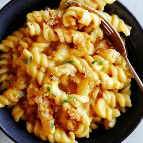 A bowl of pumpkin mac and cheese for a fork in the pasta.