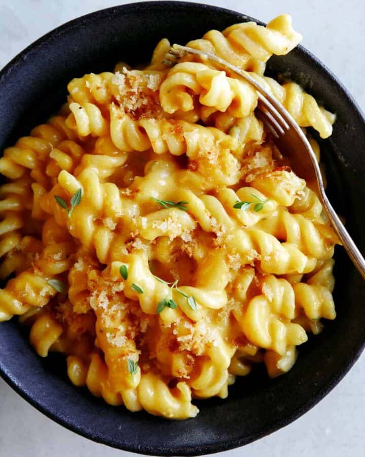 A bowl of pumpkin mac and cheese for a fork in the pasta.