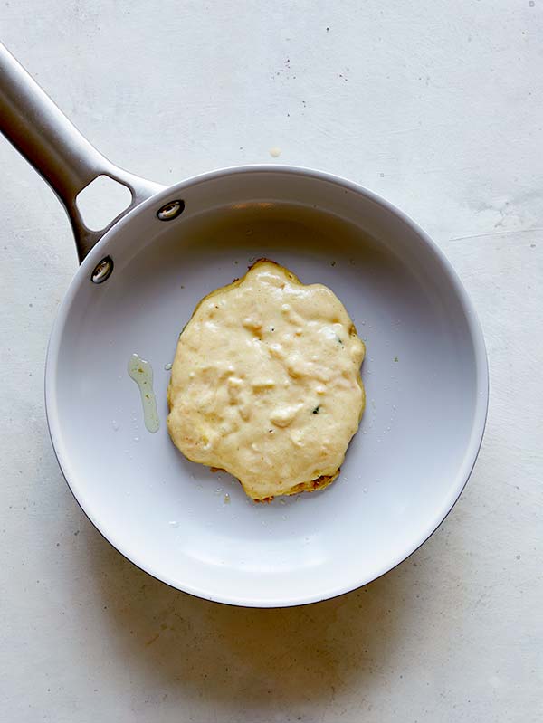 A pancake being cooked in a skillet so you can see the air bubbles rise.