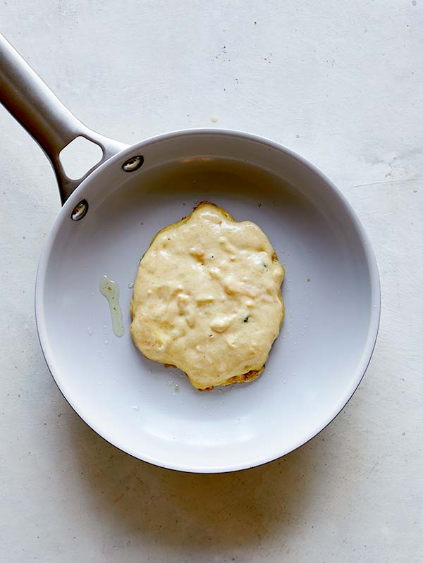 A pancake being cooked in a skillet so you can see the air bubbles rise. 