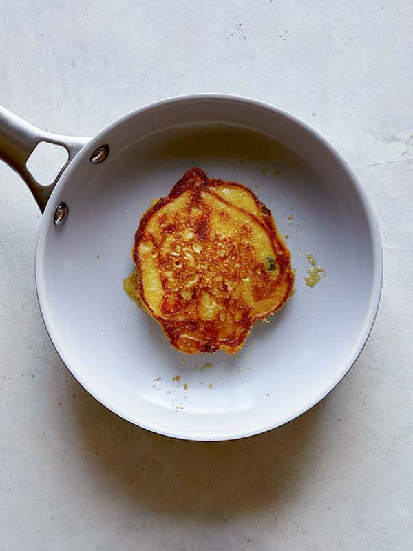 A cooked pancake in a skillet flipped to reveal with cooked and crispy side. 