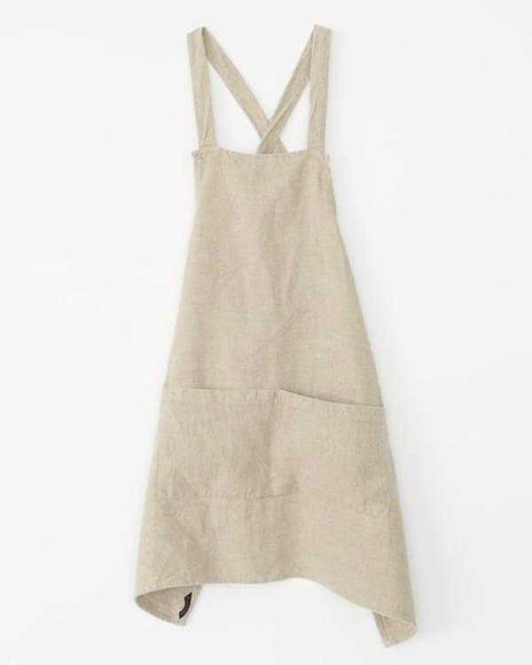 A linen crossback apron on a white background. 