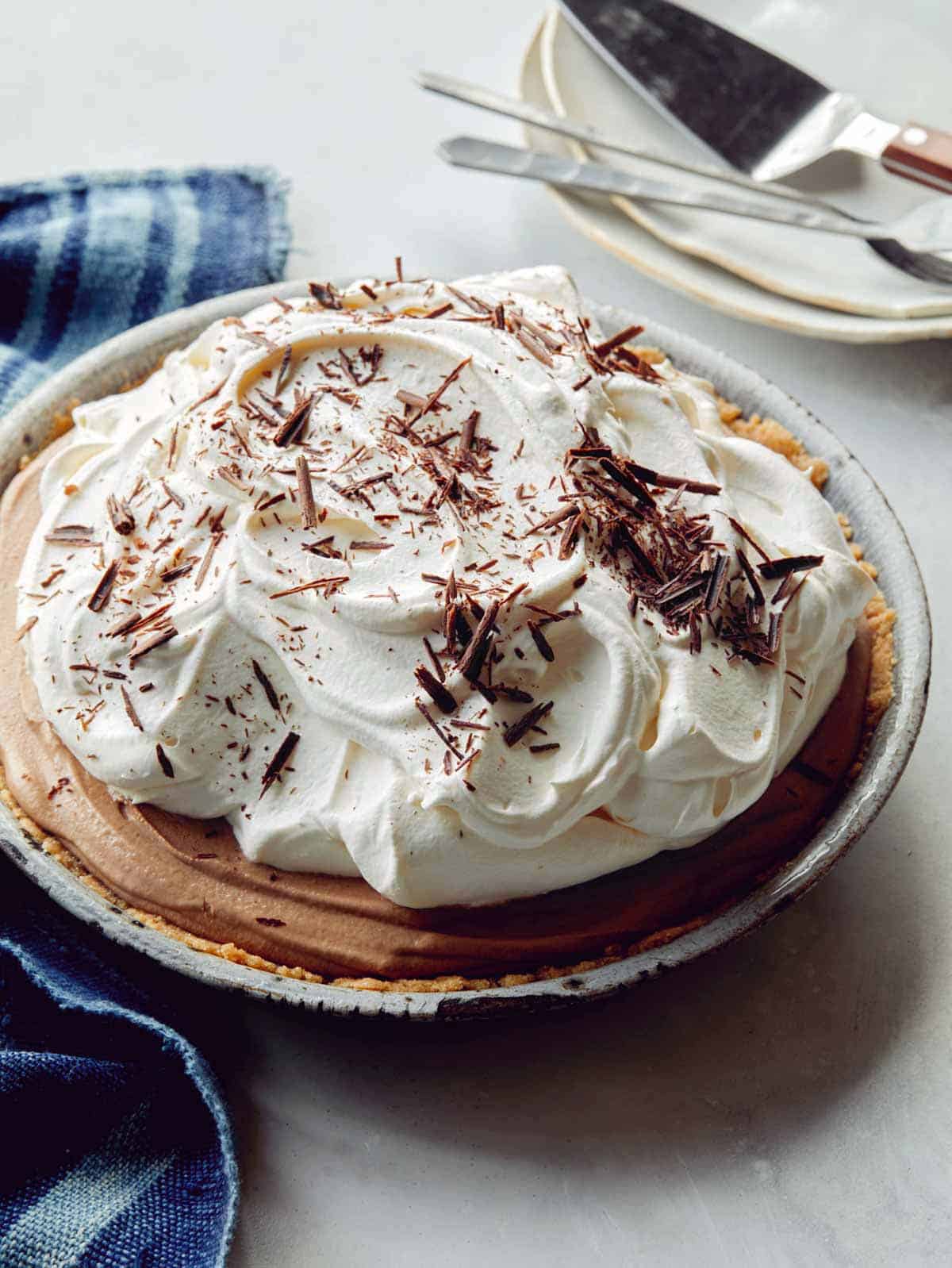 A whole french silk pie with some plates in the background.