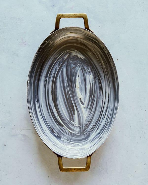 A buttered oval baking dish on a surface.
