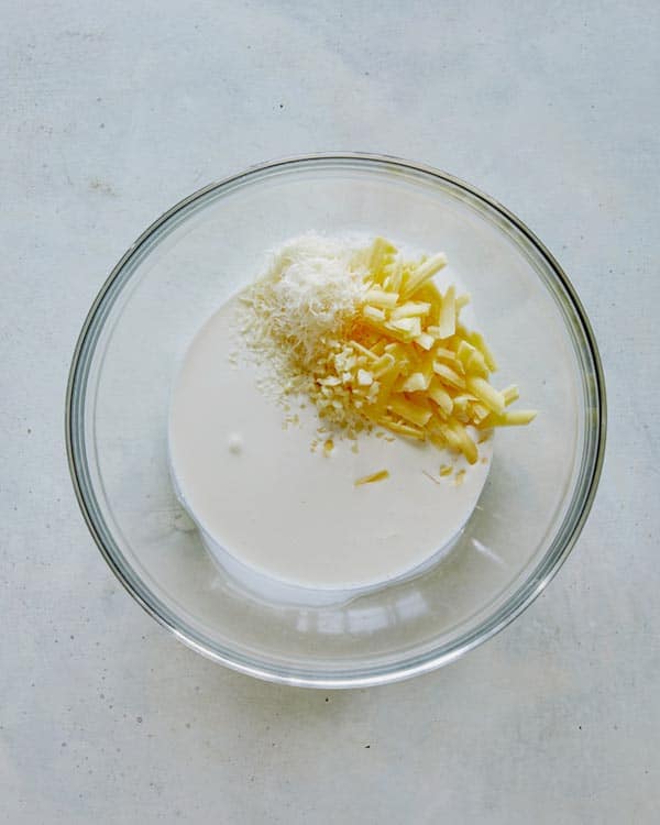 Cream, garlic, and cheese in a bowl for potatoes gratin.