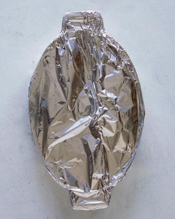 A casserole dish with potatoes gratin and tin foil on top.