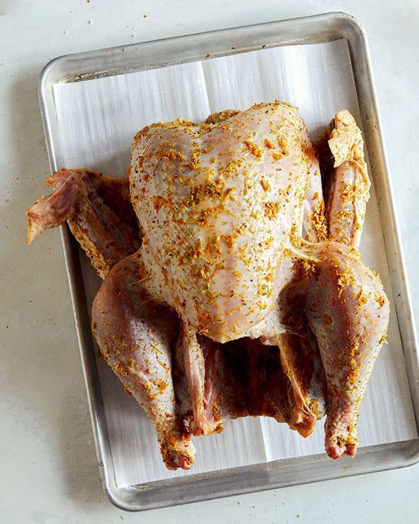 A turkey on a baking sheet rubbed with a citrus dry brine. 