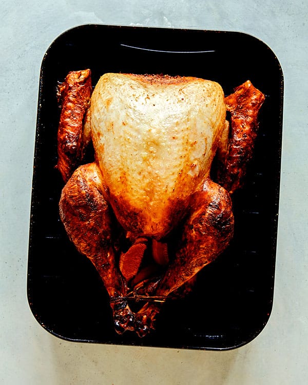 A turkey in a roasting pan being roasted.