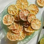 Dehydrated lime slices on a plate next to a fresh lime.