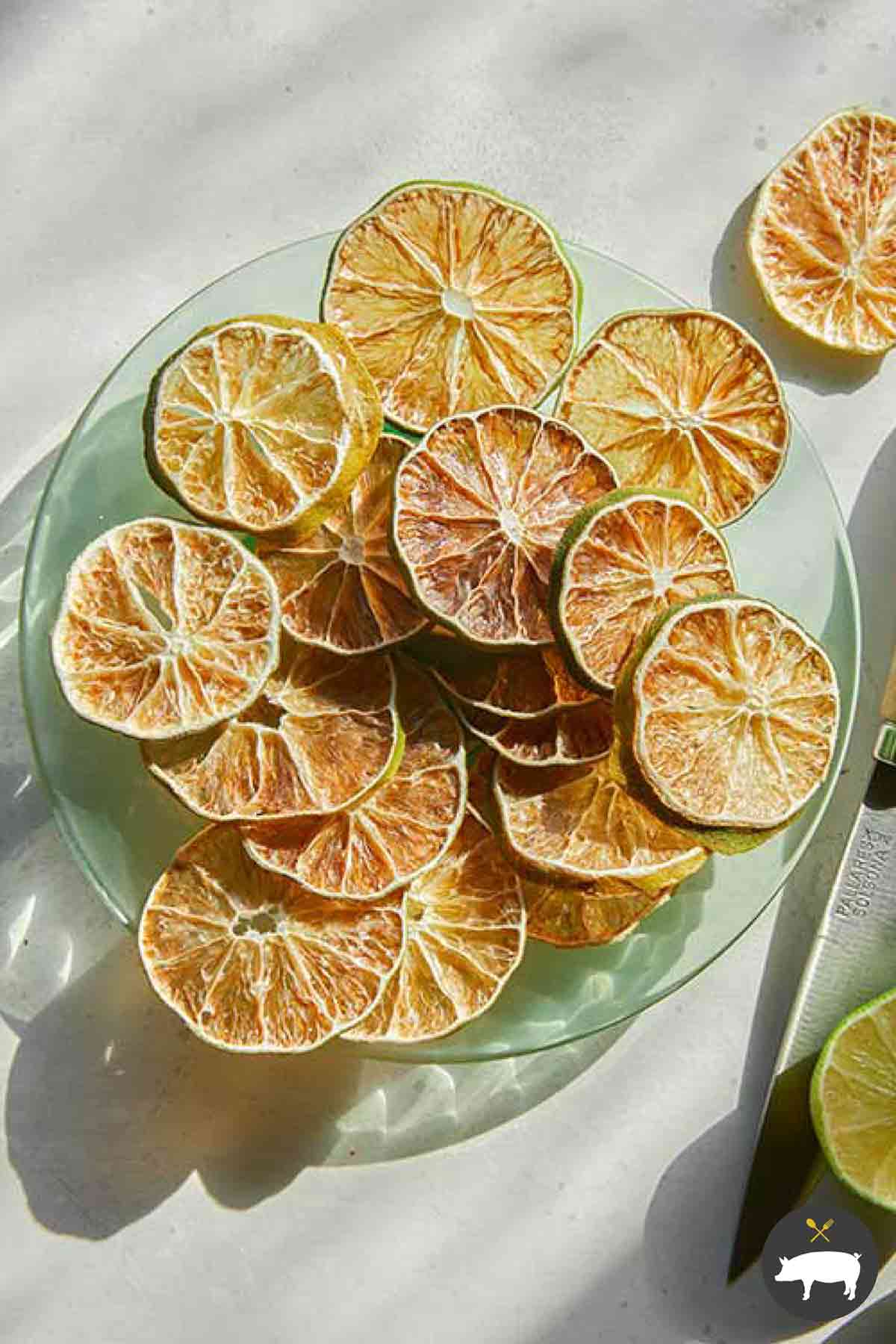 Dehydrated lime slices on a plate next to a fresh lime.
