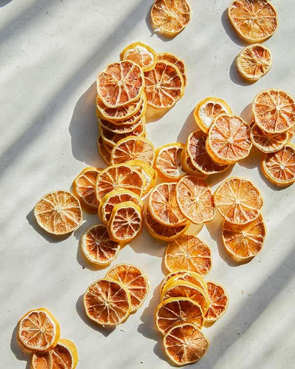 Dehydrated lemon slices spread out on a kitchen counter. 