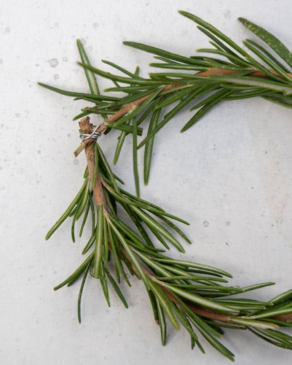 Attaching the ends of a rosemary sprig with floral wire to make a wreath. 