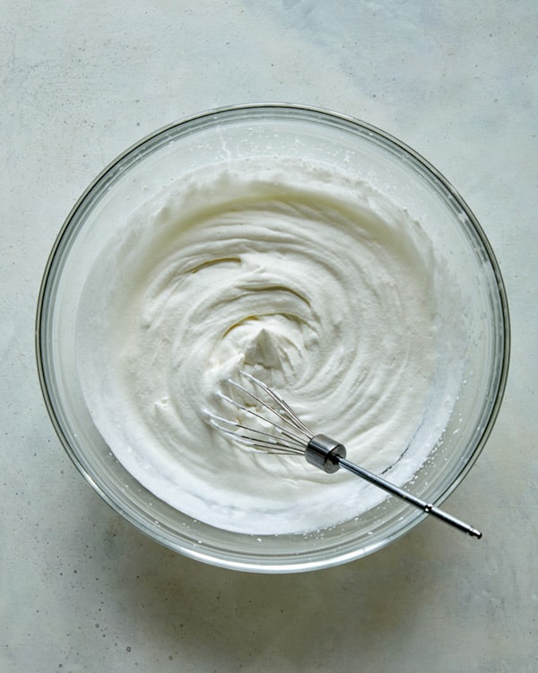 Whipped cream freshly whipped in a glass bowl.