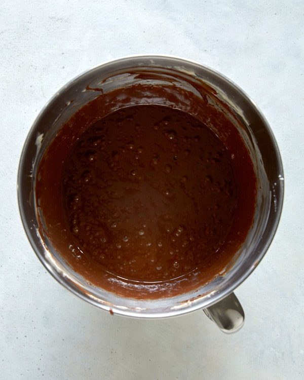 Butter and chocolate combined into a bowl with a stand mixer.