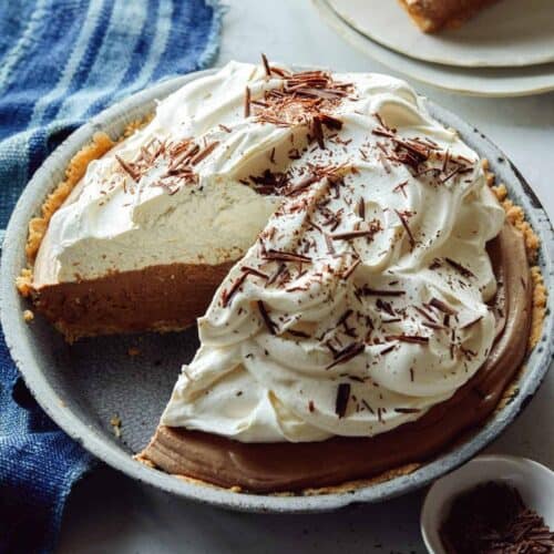 French silk pie with a slice out on a plate next to it.