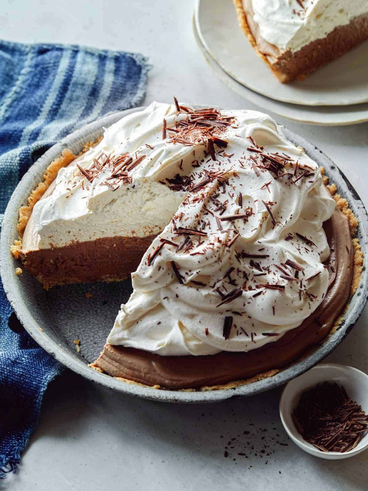 A whole french silk pie with a slice taken out and a piece next to it. 