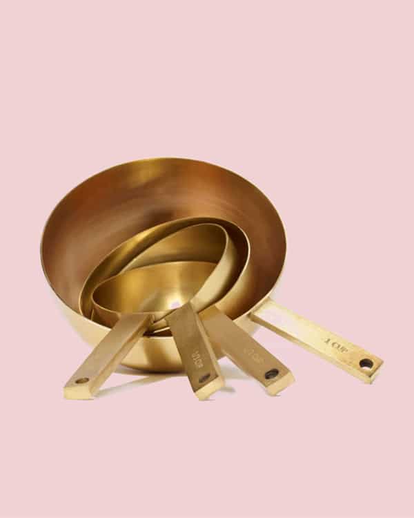 Gold measuring spoons on a pink background. 