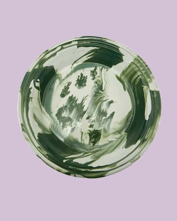A swirled green bowl on a purple background. 