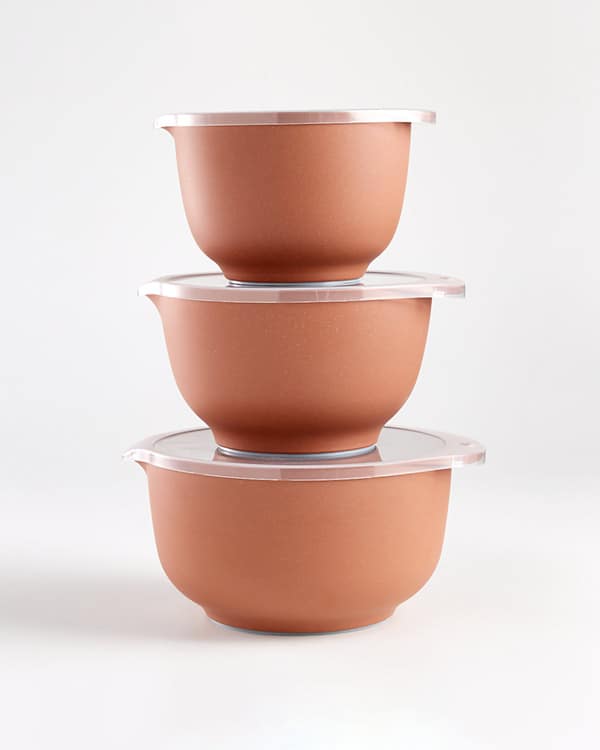 A stack of three pantry bowls with lids on a white surface. 