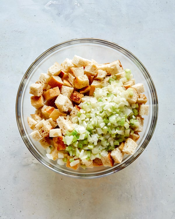 Bread crumbs with celery and onion on top in a glass bowl.