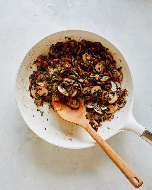 A skillet with mushrooms and herbs.