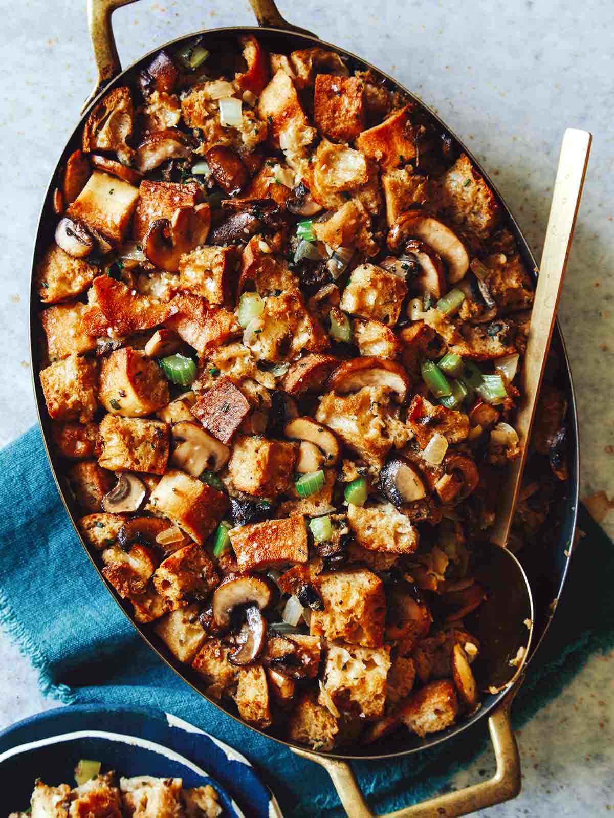 Mushroom and sage stuffing in a baking dish with a spoon in it. 