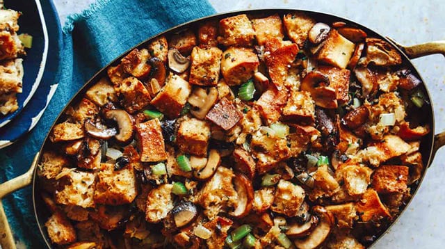 Mushroom and sage stuffing in a baking dish with some in a bowl next to it.