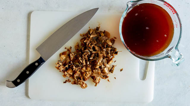 Dried mushrooms being chopped with broth next to it.