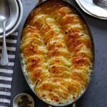 Potato gratin in a casserole dish with some bowls next to it.