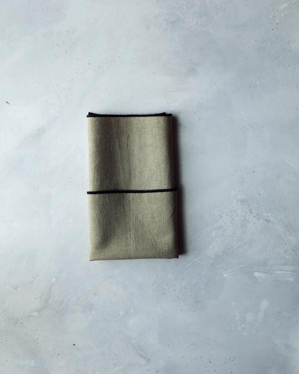 Folding a napkin on a kitchen counter for rosemary sprig place cards.