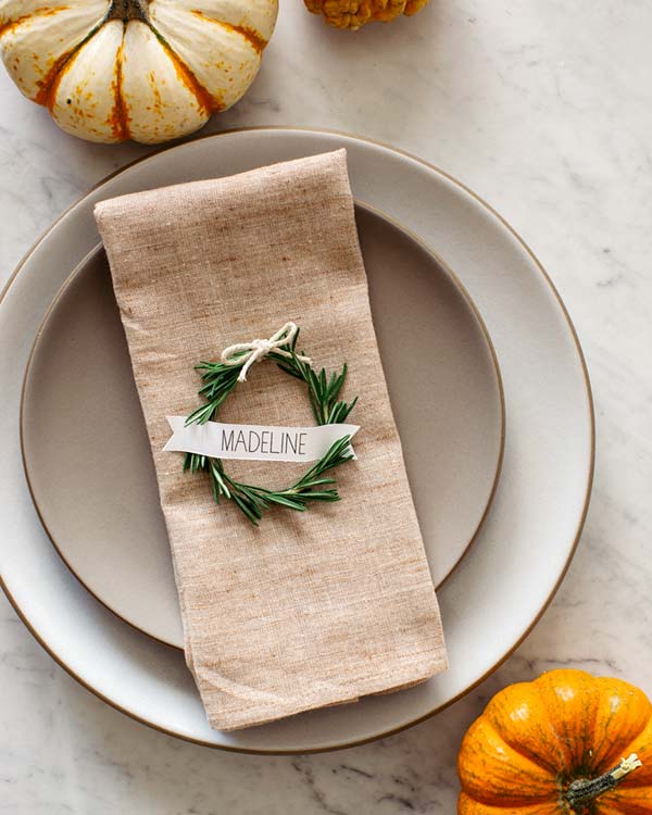Rosemary wreath place cards on a napkin on a plates.