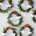 Six rosemary wreath place cards on a table spread out.