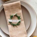 Rosemary wreath place cards on a napkin on a plates.