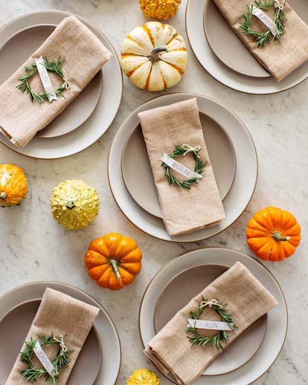 Rosemary wreath place cards on napkins on plates.