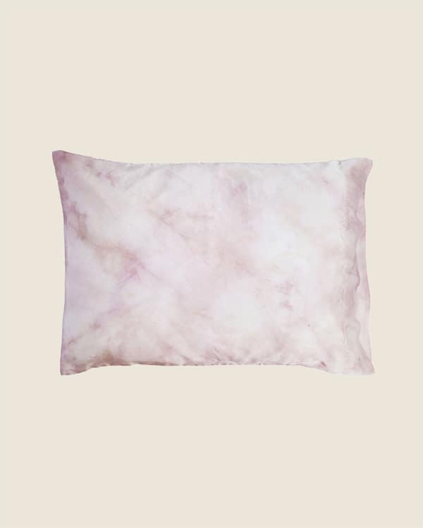 A rose colored tie dyed pillowcase on a tan background. 