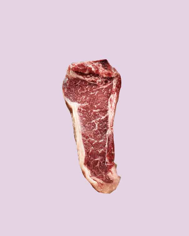 A raw steak cut out on a purple background. 