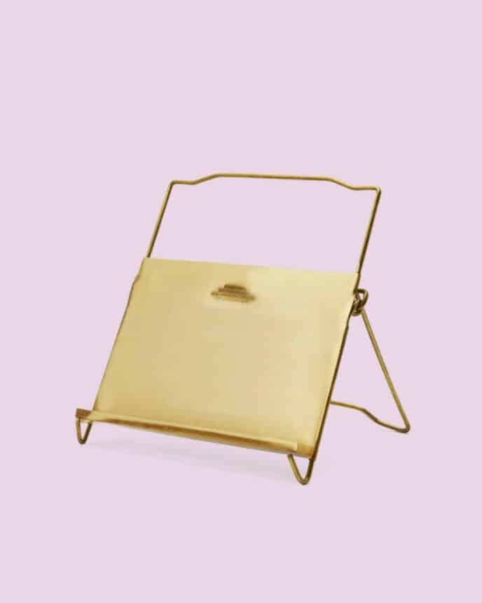 A brass tablet and cookbook stand on a purple background. 