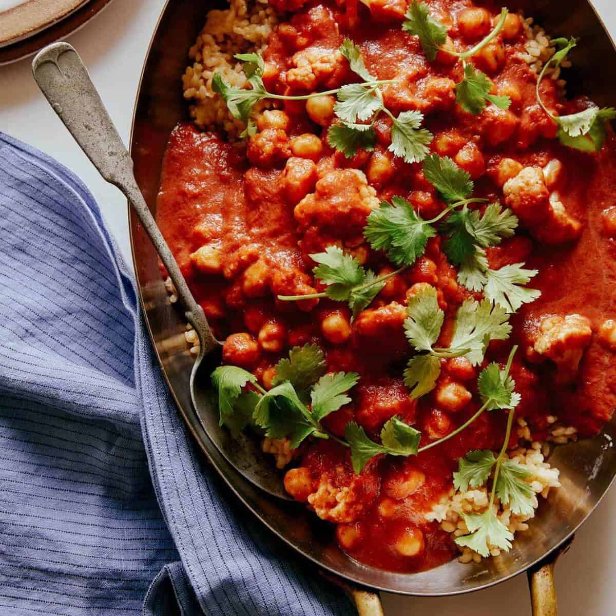 Spicy vegan chickpea and cauliflower curry with a spoon, a heathy dinner recipe.