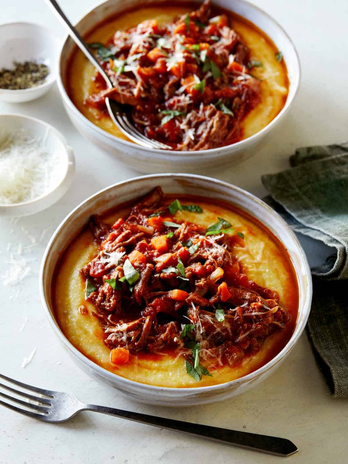 Two bowls of beef ragu with fork on the side.