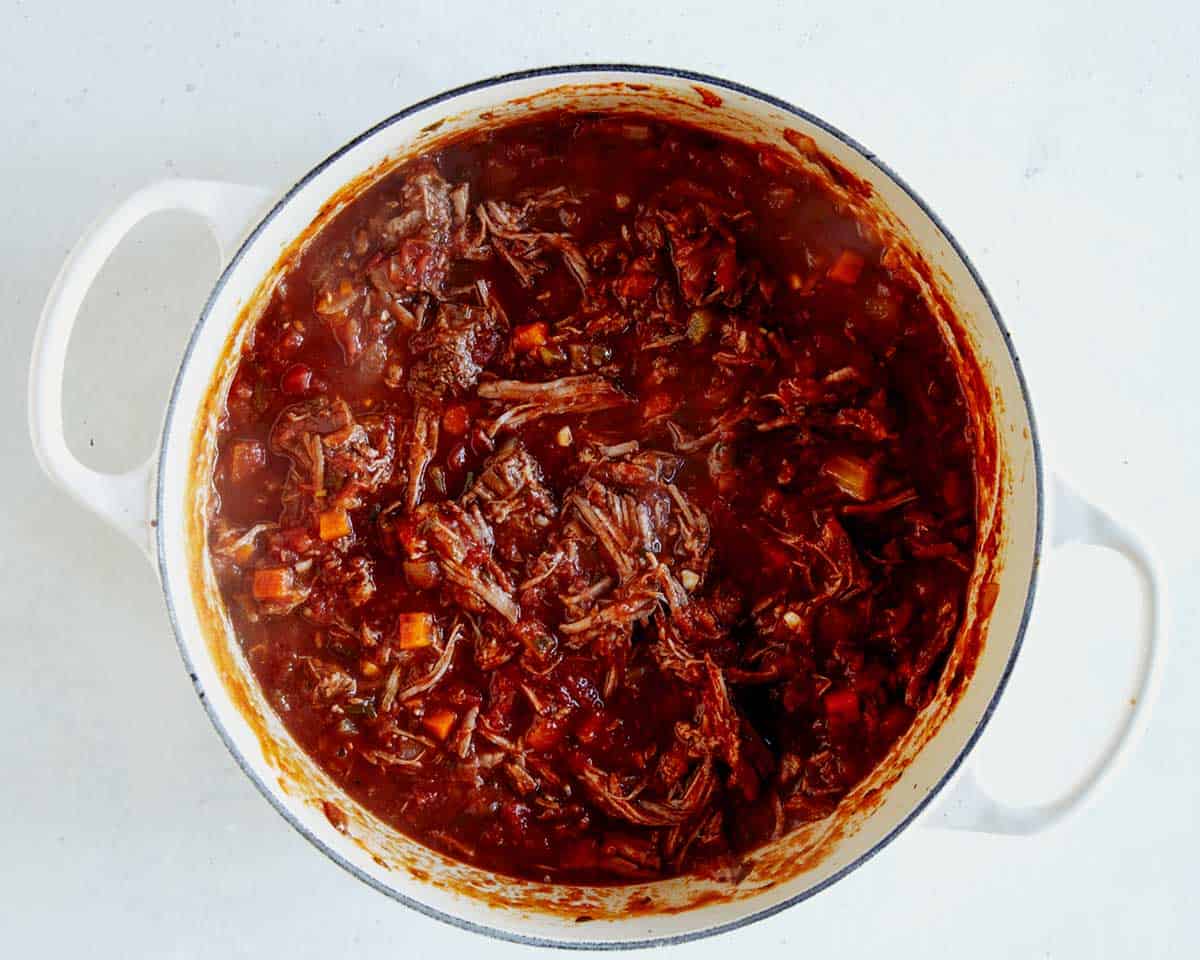 Braised beef shredded in a stock pot.