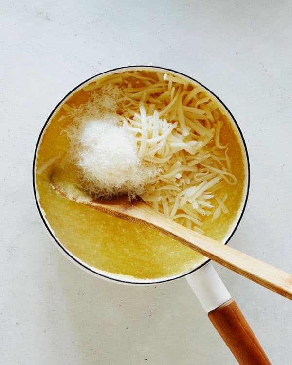 Polenta in a pot with cheese and a wooden spoon.
