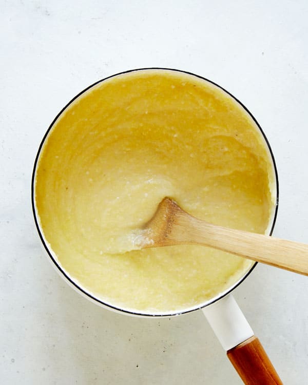 Polenta in a pot with a wooden spoon.