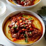 Braised beef ragu in two bowls with forks on the side.